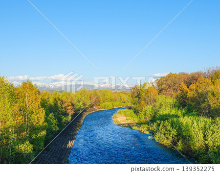 The scenery of the Biei River flowing through Biei Town, Hokkaido, from spring to early summer, and the Daisetsuzan mountain range. The scenery of the Biei River flowing through Biei Town, Hokkaido, from spring to early summer, and the Daisetsuzan mountain range. 139352275