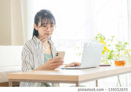A young woman using a computer and a smartphone A young woman using a computer and a smartphone 139352635