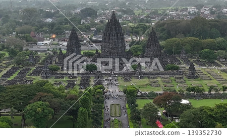 An enchanting evening aerial shot of the Prambanan Hindu Temple complex in Indonesia, featuring its iconic towering stone spires illuminated against a misty twilight sky and a sprawling cityscape. An enchanting evening aerial shot of the Prambanan Hindu Temple complex in Indonesia, featuring its iconic towering stone spires illuminated against a misty twilight sky and a sprawling cityscape. 139352730