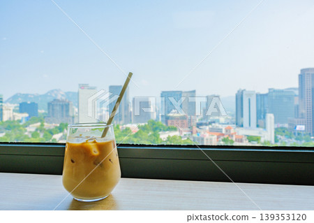 Seoul, South Korea - Jun. 25, 2023 : A refreshing glass of cafe latte at Jeongdong Observatory overlooking the historic palace and city skyline Seoul, South Korea - Jun. 25, 2023 : A refreshing glass of cafe latte at Jeongdong Observatory overlooking the historic palace and city skyline 139353120