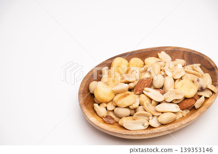 Close-up of a wooden plate of mixed nuts placed against a white background. Close-up of a wooden plate of mixed nuts placed against a white background. 139353146