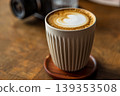 Wooden desktop pour-over latte art with heart-shaped latte art and camera 139353508