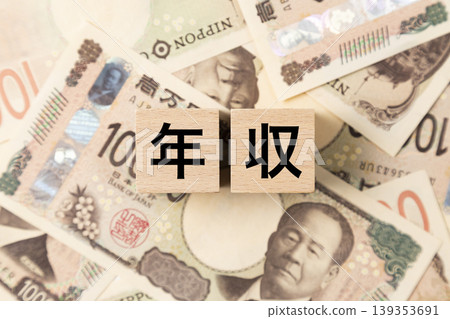 一塊寫著「年收入」的紙幣和許多10,000日圓的鈔票。 一塊寫著「年收入」的紙幣和許多10,000日圓的鈔票。 139353691