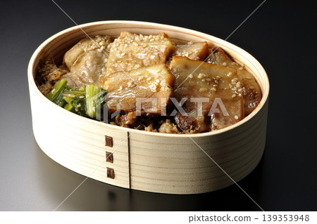 A photo of a grilled pork bento box against a black background. A photo of a grilled pork bento box against a black background. 139353948