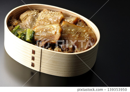 A photo of a grilled pork bento box against a black background. A photo of a grilled pork bento box against a black background. 139353950