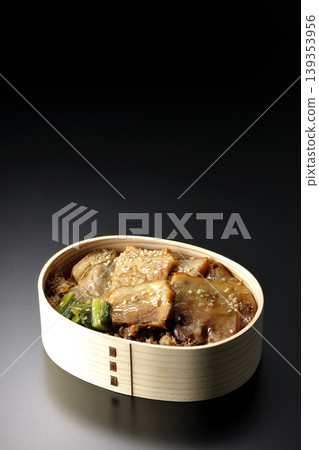 A photo of a grilled pork bento box against a black background. A photo of a grilled pork bento box against a black background. 139353956