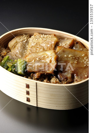 A photo of a grilled pork bento box against a black background. A photo of a grilled pork bento box against a black background. 139353957