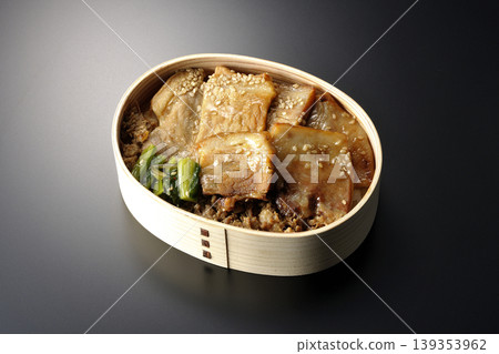 A photo of a grilled pork bento box against a black background. A photo of a grilled pork bento box against a black background. 139353962