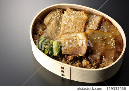 A photo of a grilled pork bento box against a black background. A photo of a grilled pork bento box against a black background. 139353966