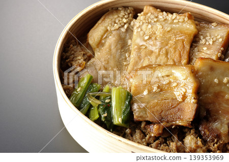 A photo of a grilled pork bento box against a black background. A photo of a grilled pork bento box against a black background. 139353969