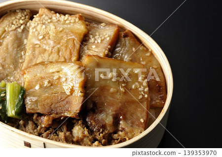 A photo of a grilled pork bento box against a black background. A photo of a grilled pork bento box against a black background. 139353970