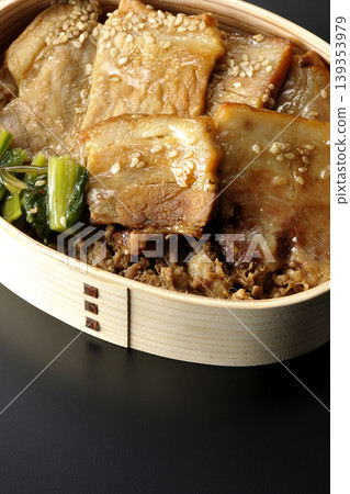 A photo of a grilled pork bento box against a black background. A photo of a grilled pork bento box against a black background. 139353979