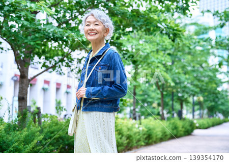 A smiling senior woman (side view) on a tree-lined street. A smiling senior woman (side view) on a tree-lined street. 139354170