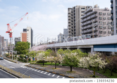 [Keikyu Main Line] Express train passing by a park with cherry blossoms in bloom. 139354230