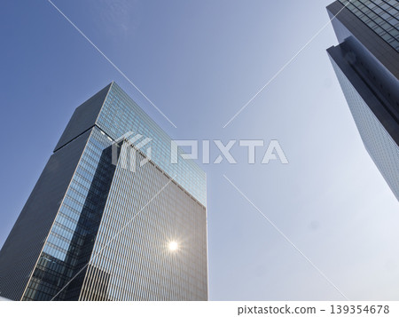 A giant glass tower gleaming in the sunlight, an office building reaching towards the blue sky. A giant glass tower gleaming in the sunlight, an office building reaching towards the blue sky. 139354678