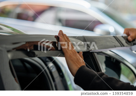 A car wrapping specialist applies a polyurethane film to the car. Detailer PPF 139354859