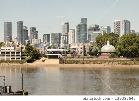 The composition of this image is grounded by the tranquil waters of the river in the foreground, leading the eye across a narrow sandy bank toward the distinctive glass-domed entrance of the Greenwich The composition of this image is grounded by the tranquil waters of the river in the foreground, leading the eye across a narrow sandy bank toward the distinctive glass-domed entrance of the Greenwich 139355645