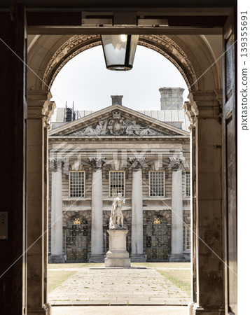 Framed by the dark silhouette of a majestic archway, the image reveals a sun-drenched courtyard that serves as a stage for classical grandeur. A regal marble statue stands atop a weathered stone Framed by the dark silhouette of a majestic archway, the image reveals a sun-drenched courtyard that serves as a stage for classical grandeur. A regal marble statue stands atop a weathered stone 139355691