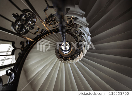 This perspective of the spiral stairs within the Chapel of St Peter and St Paul at the Old Royal Naval College, Greenwich, transforms a functional element into a stunning geometric masterpiece. This perspective of the spiral stairs within the Chapel of St Peter and St Paul at the Old Royal Naval College, Greenwich, transforms a functional element into a stunning geometric masterpiece. 139355700