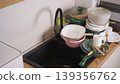 Kitchen sink overflowing with a pile of unwashed dirty dishes, bowls, and cooking pots 139356762