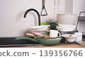 Kitchen sink overflowing with a pile of dirty dishes, plates, and pots after a meal 139356766
