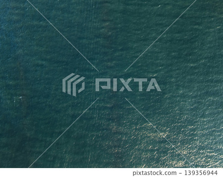 Ocean waves reflect sunlight over deep blue water surface 139356944