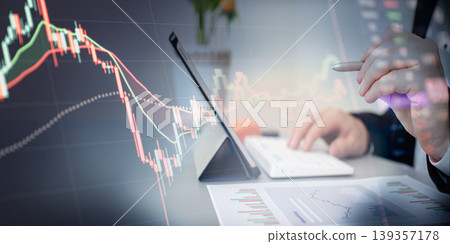 Financial analyst working with tablet and reports. Double exposure of businessman using a stylus pen and digital stock market chart showing volatility and downtrend. 139357178
