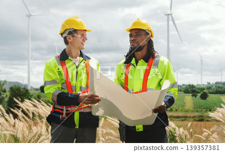 Two engineers stand outdoors, reviewing blueprints together 139357381