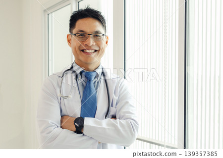 Smiling doctor stands confidently in white coat Smiling doctor stands confidently in white coat 139357385