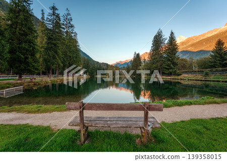 Wooden bench overlooking alpine mountain lake in evening Wooden bench overlooking alpine mountain lake in evening 139358015