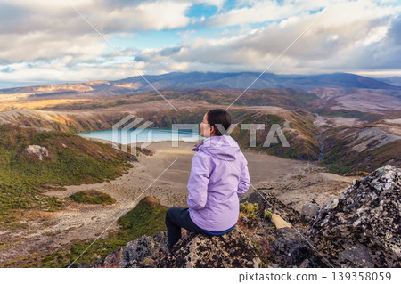 Female hiker sitting on top of Tama Lakes viewpoint with volcanoc hiding in cloud at Tongariro national park, New Zealand 139358059