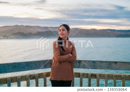 Woman posing on lighthouse by pacific ocean in the evening at New Zealand Woman posing on lighthouse by pacific ocean in the evening at New Zealand 139358064