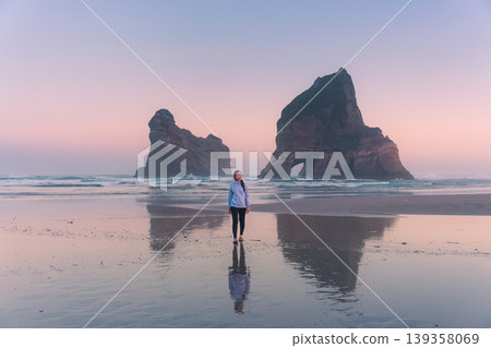 Female tourist walking and enjoying on Wharariki beach with Archway Islands at New Zealand Female tourist walking and enjoying on Wharariki beach with Archway Islands at New Zealand 139358069