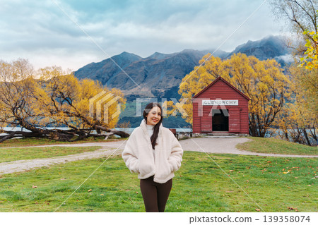 Asian woman traveling in Glenorchy with red boatshed by Lake Wakatipu on autumn at New Zealand Asian woman traveling in Glenorchy with red boatshed by Lake Wakatipu on autumn at New Zealand 139358074