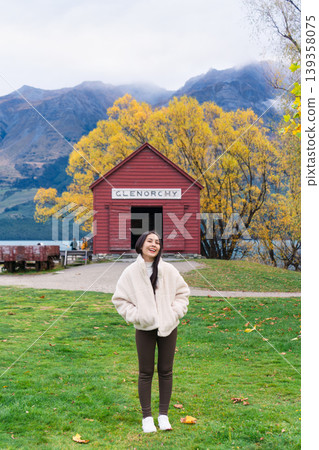 Asian woman traveling in Glenorchy with red boatshed by Lake Wakatipu on autumn at New Zealand 139358075