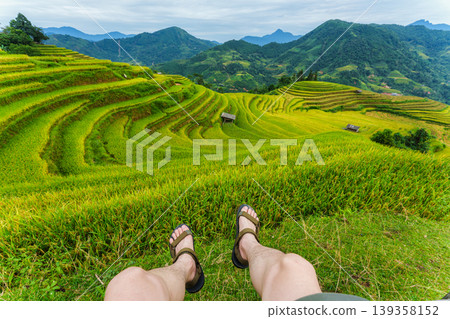 Legs of tourist relaxing on lush rice field terraces in farmland at countryside Legs of tourist relaxing on lush rice field terraces in farmland at countryside 139358152