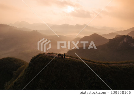Sunrise over Ba Guang grass hill, Mountain range and fog along with villager bringing their horse to graze on the mountain Sunrise over Ba Guang grass hill, Mountain range and fog along with villager bringing their horse to graze on the mountain 139358166