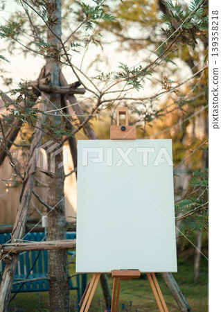 Blank canvas set on wooden easel placed front of wedding event in rustic style Blank canvas set on wooden easel placed front of wedding event in rustic style 139358218