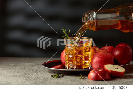 Apple juice is poured from a bottle into a glass. Apple juice is poured from a bottle into a glass. 139360021