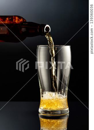 Pouring beer from a bottle into a glass. Pouring beer from a bottle into a glass. 139360036