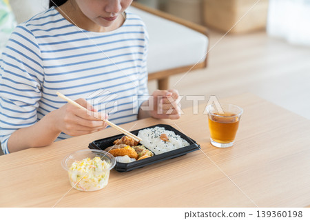 A young woman's hands as she eats a convenience store bento box. A young woman's hands as she eats a convenience store bento box. 139360198