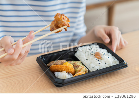 一位年輕女子正在吃便利商店的便當盒。 一位年輕女子正在吃便利商店的便當盒。 139361296