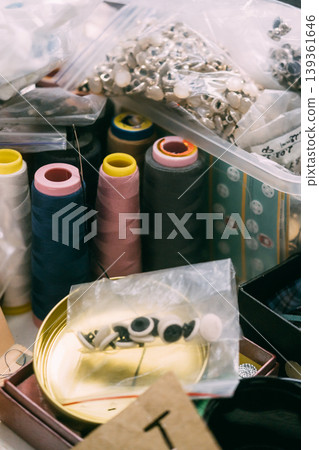 Sewing supplies. Tailor accessories. Colorful thread spools placed with storage box buttons for professional garment manufacturing. Sewing supplies. Tailor accessories. Colorful thread spools placed with storage box buttons for professional garment manufacturing. 139361646