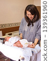A mother changing her newborn's diaper in the maternity ward. 139361960