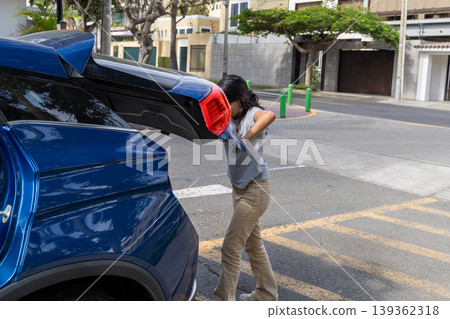 A teenager is pulling a blue car out of a parking lot A teenager is pulling a blue car out of a parking lot 139362318