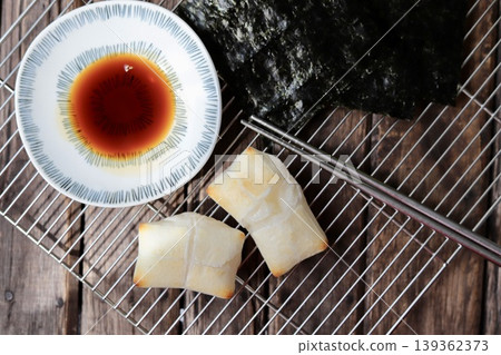 烤麻糬配磯部燒、醬油和烤海苔,放在蛋糕冷卻器上。 烤麻糬配磯部燒、醬油和烤海苔,放在蛋糕冷卻器上。 139362373