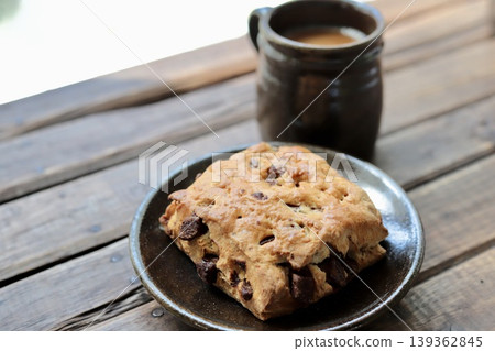 Enjoying chocolate chunk scones and café au lait in Yachimun pottery during coffee time. Enjoying chocolate chunk scones and café au lait in Yachimun pottery during coffee time. 139362845