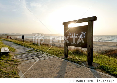 透過京都府京丹後市阿彌町濱爪夕日浦海灘沙灘上的「日落步道」指示牌,可以看到夕陽西下。 透過京都府京丹後市阿彌町濱爪夕日浦海灘沙灘上的「日落步道」指示牌,可以看到夕陽西下。 139363347