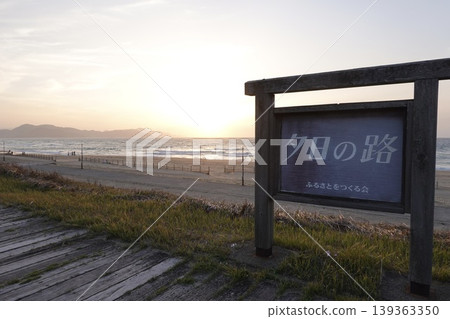 透過京都府京丹後市阿彌町濱爪夕日浦海灘沙灘上的「日落步道」指示牌,可以看到夕陽西下。 透過京都府京丹後市阿彌町濱爪夕日浦海灘沙灘上的「日落步道」指示牌,可以看到夕陽西下。 139363350