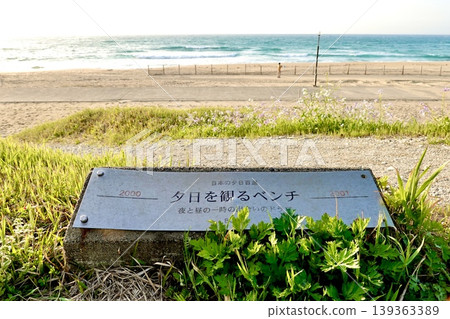 Sign for a bench for watching the sunset on the Sunset Path along the sandy beach at Yuhigaura Beach, Hamazume, Amino-cho, Kyotango City, Kyoto Prefecture Sign for a bench for watching the sunset on the Sunset Path along the sandy beach at Yuhigaura Beach, Hamazume, Amino-cho, Kyotango City, Kyoto Prefecture 139363389